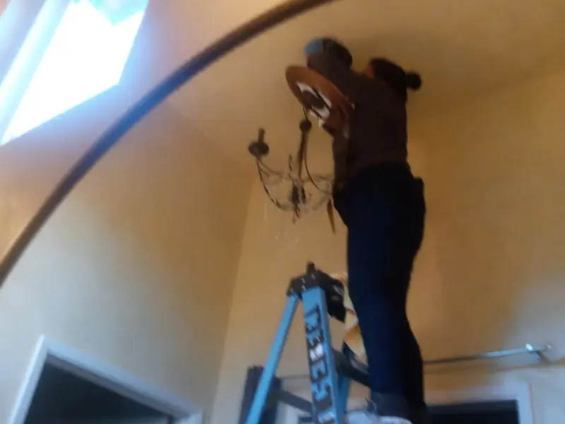 Electrician installing a chandelier in a Windham residence